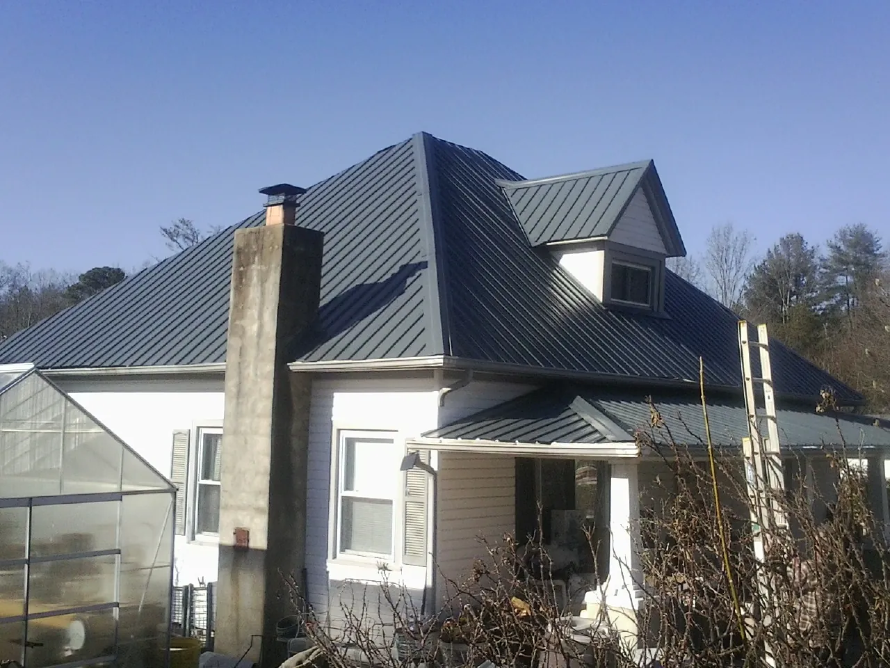 Dark blue standing seam metal roof on a white farmhouse with dormer — Slate & Tile Roof Repair by Roofing Brothers in Morristown
