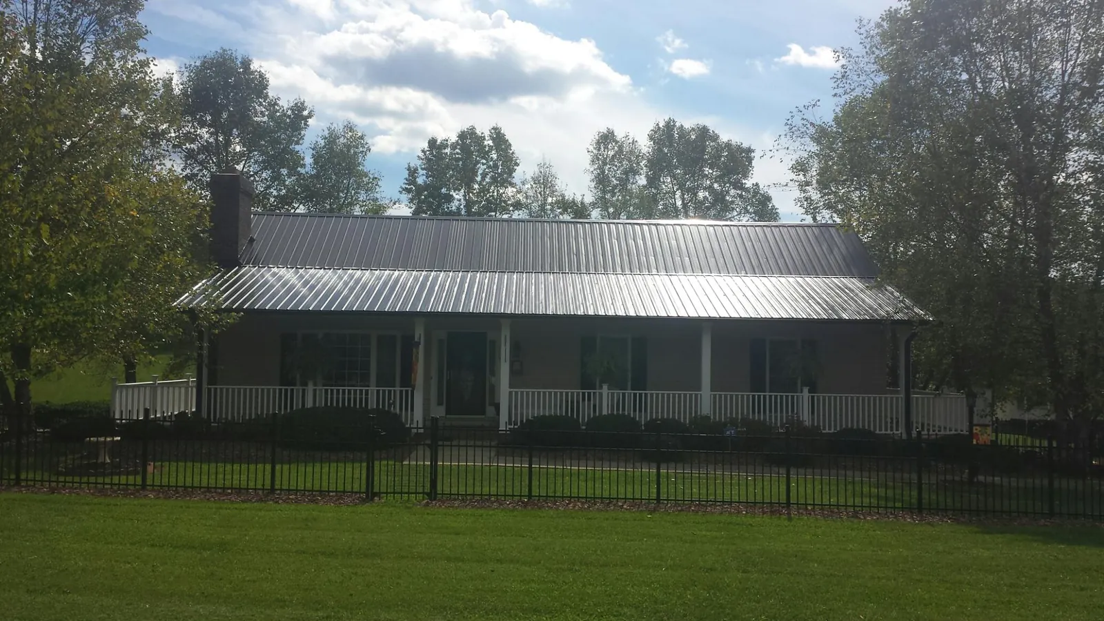 Gray metal roof on a brick ranch with a full width front porch — Gutter Guard Installation work by our crew in Morristown